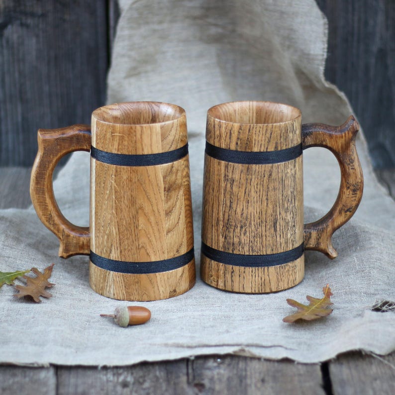 Hand holding the oak mug, showcasing its comfortable grip and natural wood finish.
