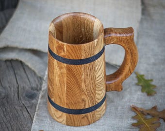 May include: A wooden beer stein with a dark brown handle and black bands around the body.
