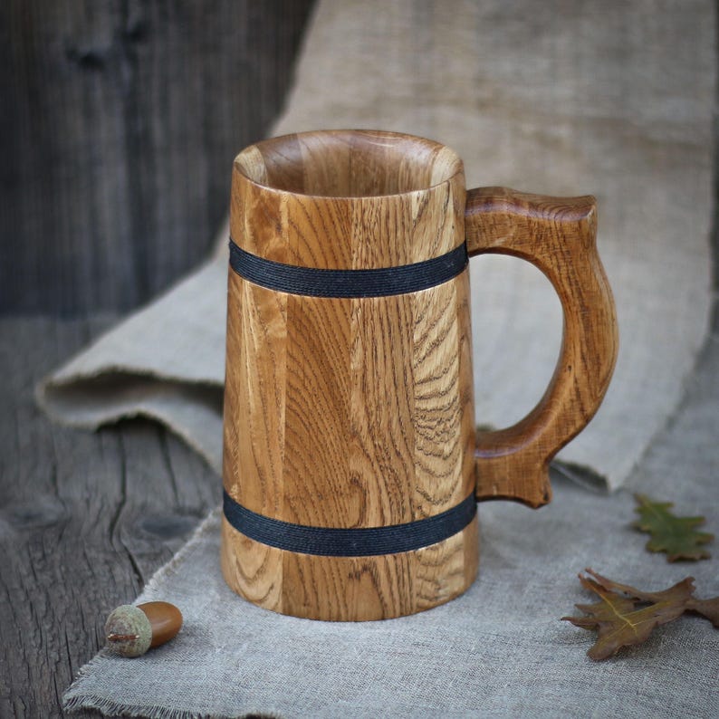 A close-up of the oak mug in soft natural lighting, emphasizing the rich details of the wood grain and beeswax finish.
