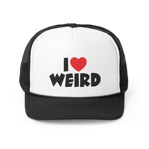 Puede incluir: Una gorra de camionero negra y blanca con un panel frontal blanco. El panel frontal tiene un corazón rojo y el texto "I ♥ WEIRD" en negro.