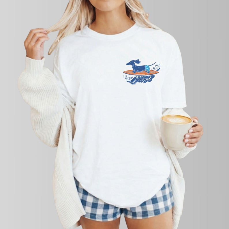 Woman wearing surfer dog pocket t-shirt at the beach with coastal background