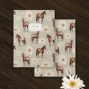 May include: A rectangular notebook with a light beige cover featuring a repeating pattern of brown horses and white daisy flowers. The front cover includes a central white rectangular label with the word NOTEBOOK printed in black text.