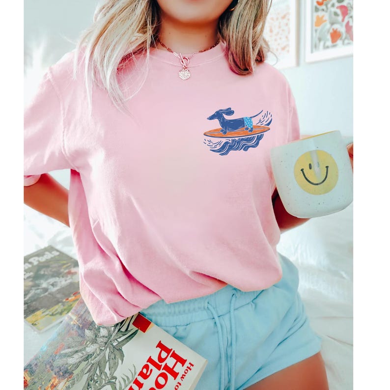 Woman wearing surfer dog pocket t-shirt at the beach with coastal background
