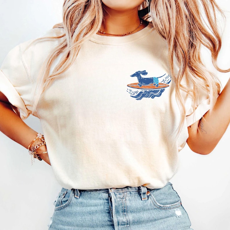Woman wearing surfer dog pocket t-shirt at the beach with coastal background