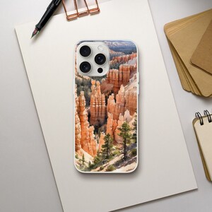 Könnte beinhalten: Eine weiße iPhone-Hülle mit einem farbenfrohen Bild einer Landschaft mit roten Felsformationen. Das Bild ist eine Nahaufnahme der Felsformationen, die hoch und schlank sind. Die Hülle hat einen Kameraausschnitt in der oberen linken Ecke.