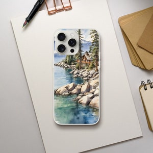 May include: A watercolor phone case featuring a scenic landscape with a lake, rocks, trees, and a house. The case has a white background and a clear design.