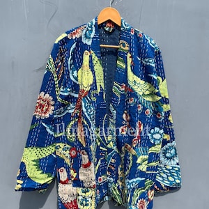 May include: A blue quilted jacket with a floral and bird print. The jacket has a long sleeve and an open front.