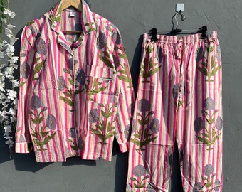 Può includere: Pigiama a righe rosa e bianche con stampa floreale. La parte superiore ha maniche lunghe e una chiusura con bottoni sul davanti. I pantaloni hanno una cintura elastica.