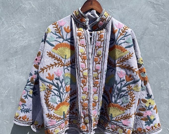 May include: A light purple jacket featuring intricate floral embroidery in shades of orange, yellow, pink, and teal. The garment has a high collar, long sleeves, and a front opening, with the embroidery pattern extending across the entire surface.