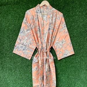 May include: A peach-coloured robe with a floral print. The robe has a tie belt and long sleeves.