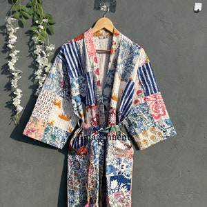 May include: A long, white cotton robe with a patchwork design featuring floral and geometric patterns in shades of blue, pink, red, and yellow. The robe has a tie belt and long sleeves.