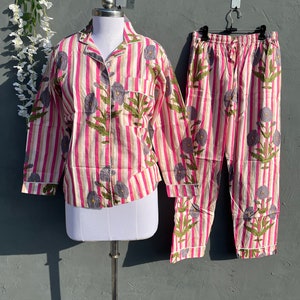 May include: A pink and white striped pajama set with a floral print. The top has long sleeves and a button-up front. The pants have an elastic waistband.