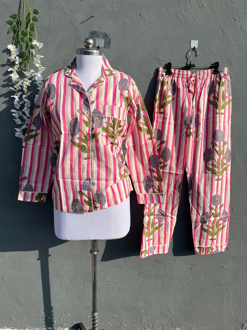 May include: A pink and white striped pajama set with a floral print. The top has long sleeves and a button-up front. The pants have an elastic waistband.