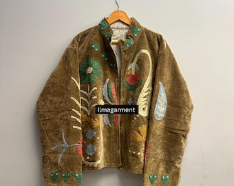 May include: A brown velvet jacket with colorful floral embroidery. The jacket features a collar and is hanging on a wooden hanger. The text "llmagarment" is visible on the front of the jacket.