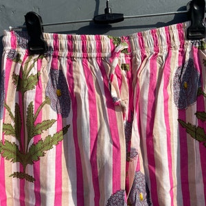 May include: Pink and white striped pajama pants with a floral print. The pants have an elastic waistband and a drawstring.