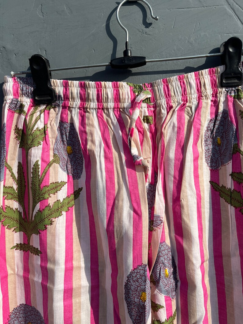 May include: Pink and white striped pajama pants with a floral print. The pants have an elastic waistband and a drawstring.