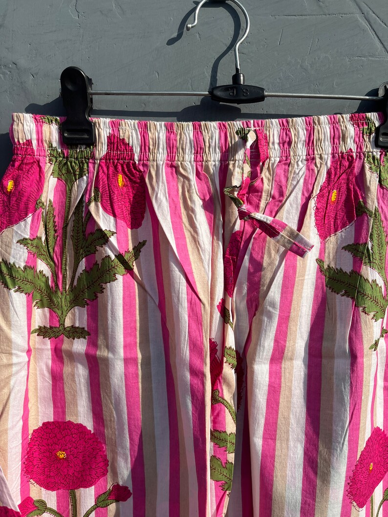 Puede incluir: Pantal&oacute;n de pijama a rayas rosa y blanco con estampado floral. El pantal&oacute;n tiene una cintura el&aacute;stica y un cord&oacute;n.