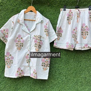 May include: White cotton pajama set with a floral print. The top has a collar and short sleeves. The shorts have an elastic waistband.