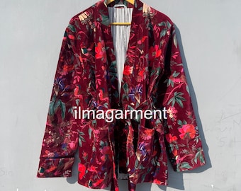 May include: A burgundy velvet kimono-style jacket with a floral pattern in red, green, and pink. The jacket has a striped lining and a matching belt. The text "ilmagarment" is visible.