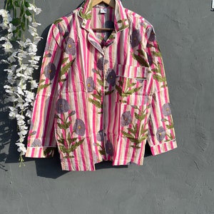 May include: A pink and white striped shirt with a floral print. The shirt has a button-up collar and long sleeves.