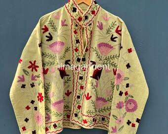 May include: A light green jacket with intricate floral embroidery in shades of pink, red, and black. The jacket features a mandarin collar and is displayed on a wooden hanger against a blue background. The text "ilmagarment" is visible on the jacket.