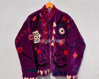 May include: A purple velvet jacket with intricate floral embroidery in red, white, and blue. The jacket features a high collar and is adorned with heart-shaped details along the hem. The text "magarment" is visible on the front.