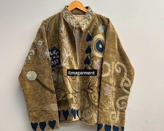 May include: A brown jacket with intricate floral embroidery in shades of blue, green, and pink. The jacket features a collared neckline and a striped lining. The cuffs and hem are adorned with blue heart-shaped details. The text "ilmagarment" is visible.