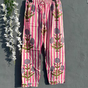 May include: Pink and white striped pajama pants with a floral print. The pants have a drawstring waistband and a relaxed fit.