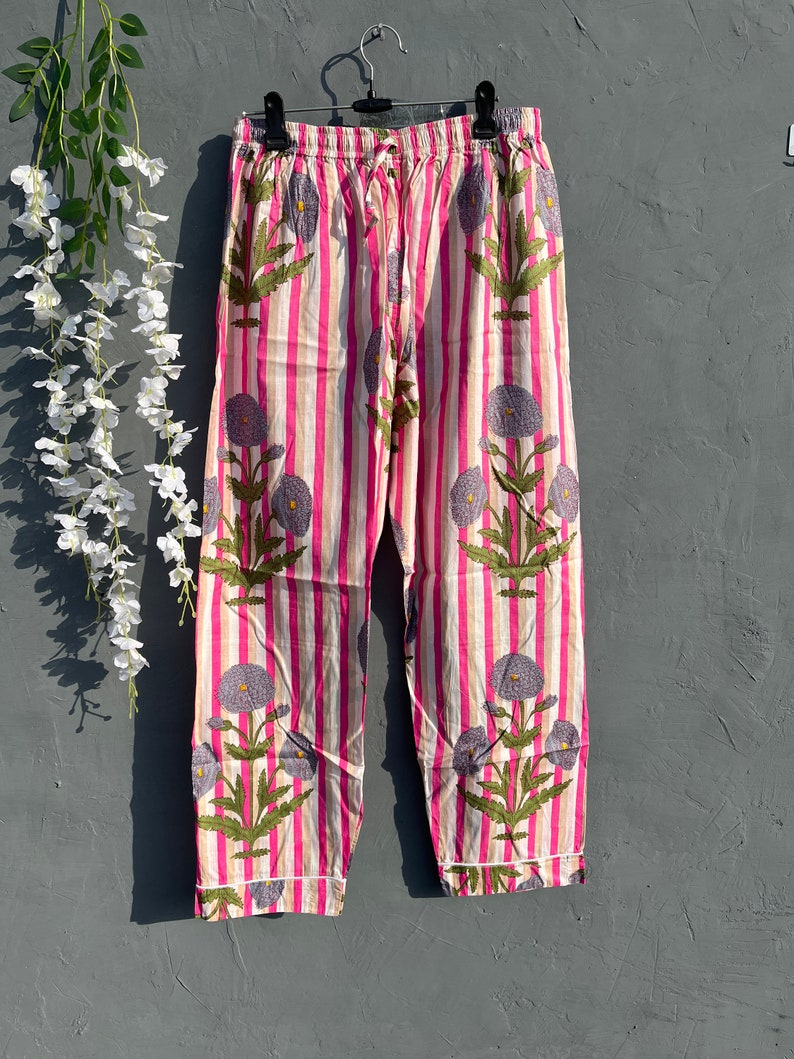 May include: Pink and white striped pajama pants with a floral print. The pants have a drawstring waistband and a relaxed fit.