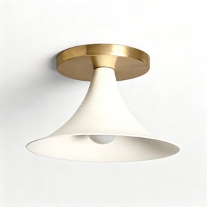 May include: A modern ceiling light fixture with a brass-colored circular base and a white, cone-shaped shade. The shade has a wide, flared bottom and a single light bulb is visible inside. The fixture is designed for indoor use.