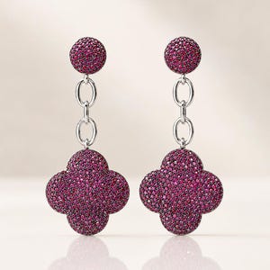 Peut inclure: Une paire de boucles d'oreilles pendantes composée d'un clou circulaire relié par deux maillons ovales argentés à un pendentif en forme de trèfle à quatre feuilles. Les clous et les pendentifs sont entièrement pavés de petites pierres magenta.