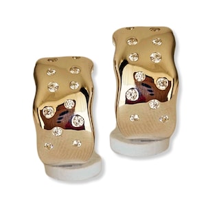 May include: A pair of gold hoop earrings with a wavy design and small clear stones set into the surface.