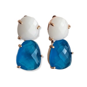 May include: A pair of dangle earrings with two teardrop-shaped stones. The top stone is white and the bottom stone is a vibrant blue.
