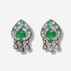 May include: A pair of dangle earrings with a teardrop-shaped design. The earrings are made of silver and feature a green gemstone surrounded by smaller green and white gemstones. The earrings have a dangling design with three teardrop-shaped gemstones.