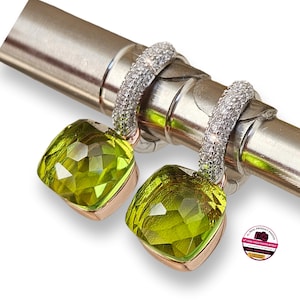 Puede incluir: Pendientes con un colgante de piedra preciosa verde claro de corte cuadrado. Los pendientes tienen un aro plateado incrustado con pequeñas piedras transparentes. El colgante está engastado en un metal color oro rosa.