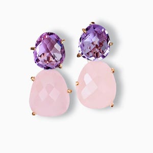 Könnte beinhalten: Ein Paar Ohrringe mit einem facettierten, ovalen, lila Amethyst-Edelstein über einem facettierten, tropfenförmigen, rosa Rosenquarz-Edelstein. Die Edelsteine sind in goldfarbenen Zinken gefasst.