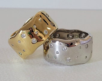 May include: Two rings with a wavy design, one is gold and the other is silver. Both rings are set with small diamonds.