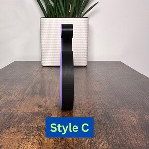 May include: A black and purple 3D printed letter C. The letter is standing on a wooden surface. The text "Style C" is visible below the letter.