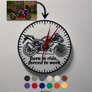 Op de afbeelding: Een witte klok met een zwarte omtrek en zwarte wijzers. De wijzerplaat van de klok heeft een zwarte lijntekening van een motorfiets met de tekst "Born to ride, forced to work". De klok is omgeven door een selectie gekleurde cirkels.