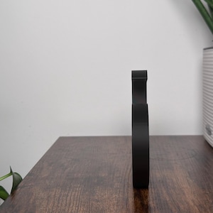 May include: A black, minimalist, modern sculpture with a rounded, organic shape. The sculpture is made of a smooth, solid material and has a sleek, contemporary design.