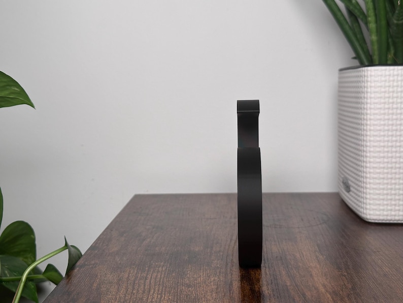 May include: A black, minimalist, modern sculpture with a rounded, organic shape. The sculpture is made of a smooth, solid material and has a sleek, contemporary design.