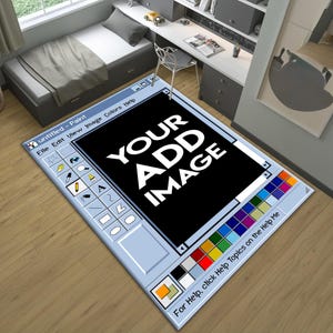 May include: A rectangular rug designed to look like the Microsoft Paint interface. The rug has a light blue border with the program's toolbar icons and colour palette. The centre has a black rectangle with the text "YOUR ADD IMAGE" in white.