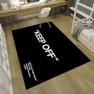 May include: Black and white rug with the text "KEEP OFF" in white lettering. The text "IKEA c/o Virgil Abloh&trade;" is also printed in white lettering, along with "Flooring", "Almhult Sweden", and "c 2019".