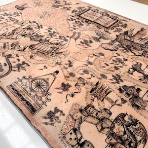 May include: A rectangular, tan-colored map with intricate black illustrations and text. The map features detailed drawings of buildings, pathways, and fantastical creatures. Text includes "The Wizarding World of Harry Potter" and "Scale of Magical Pen".