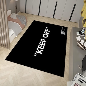 May include: Black and white rug with the text "KEEP OFF" in white lettering. The rug is made of a soft, plush material and is perfect for adding a touch of modern style to any room.