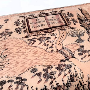 May include: A detailed map with the text "The Wizarding World of Harry Potter" in a decorative frame. The map features illustrations of a castle, trees, a bridge, and the word "Lake". The map is in shades of brown and tan.