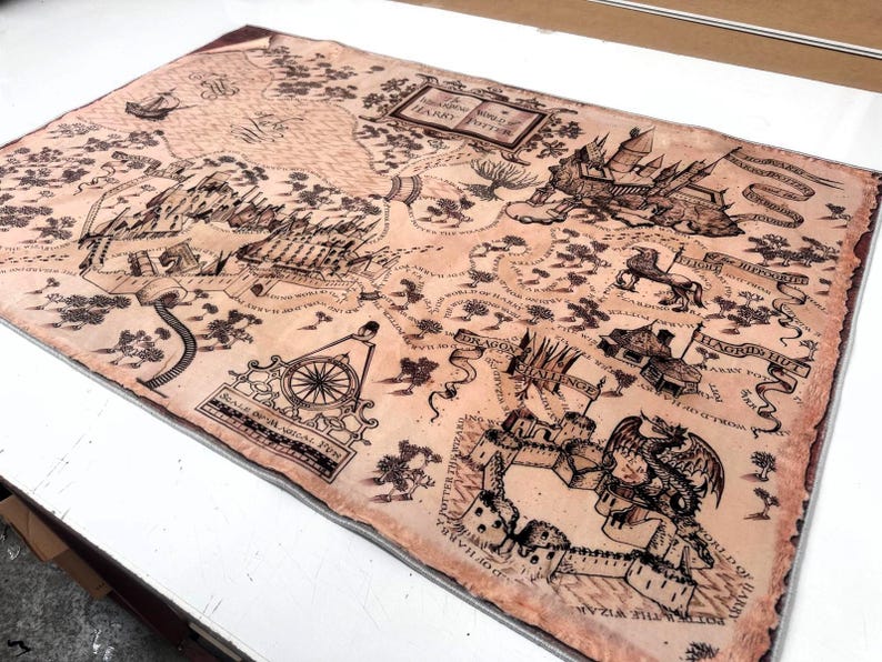 May include: A rectangular, tan-colored map with black illustrations and text. The map features detailed drawings of castles, ships, and other fantastical elements. The text includes the title "The Wizarding World of Harry Potter".