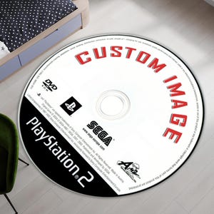 May include: A white PlayStation 2 game disc with a black border. The disc has red text that says "CUSTOM IMAGE" and "SEGA" in black text. The disc also has a black and white PlayStation 2 logo.