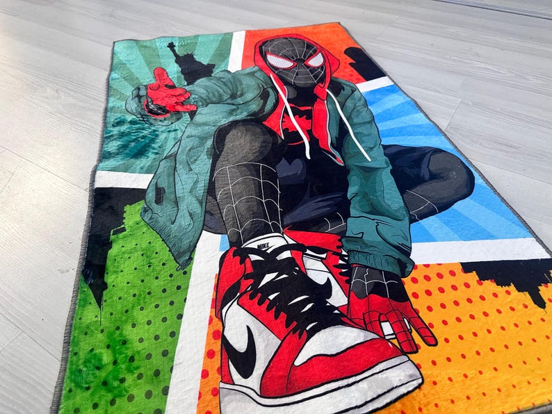 May include: A colorful rug featuring a cartoon superhero wearing a red and black suit and red and black sneakers. The rug has a comic book style design with red, blue, green, yellow, and white colors.