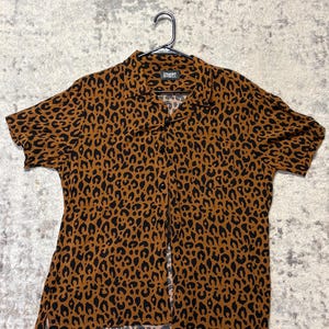 May include: A white ceramic mug with a black handle and the text "But First, Coffee" in a bold, black font. The mug is set against a neutral background, highlighting its simple design.